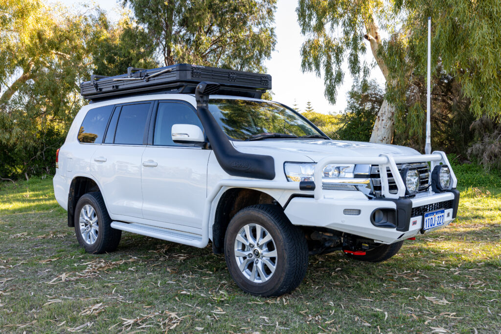 White Toyota LandCruiser 200 Series fitted with an ARB Summit bull bar, Safari snorkel, Intrepid rooftop tent and touring accessories.