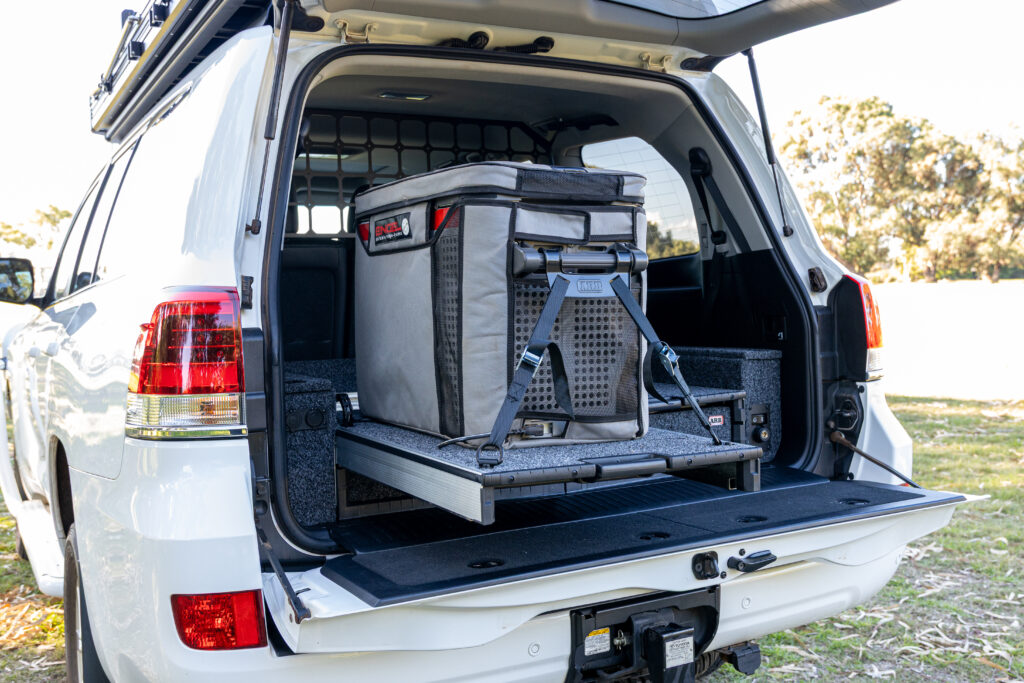 ARB fridge slide extended with portable fridge secured inside the rear of a Toyota LandCruiser 200 Series.