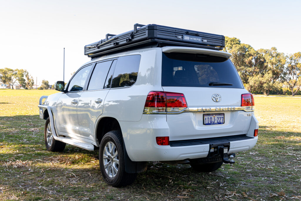 Rear three-quarter view of a Toyota LandCruiser 200 Series fitted with an ARB Intrepid rooftop tent and touring accessories.