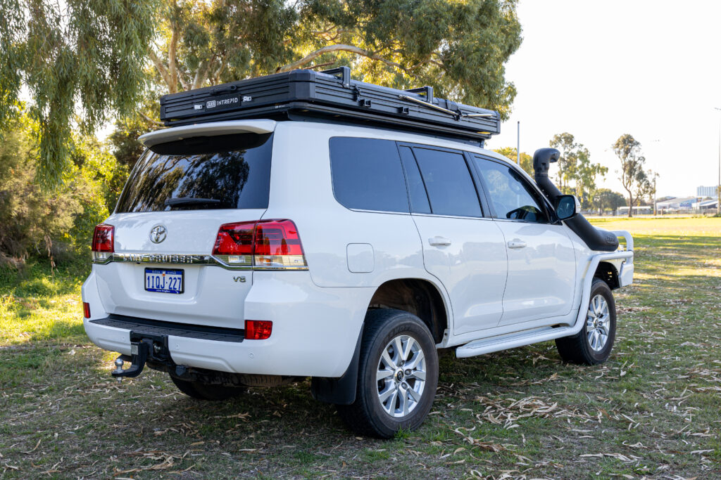 Rear angle of a Toyota LandCruiser 200 Series showcasing the Intrepid rooftop tent and tow setup.
