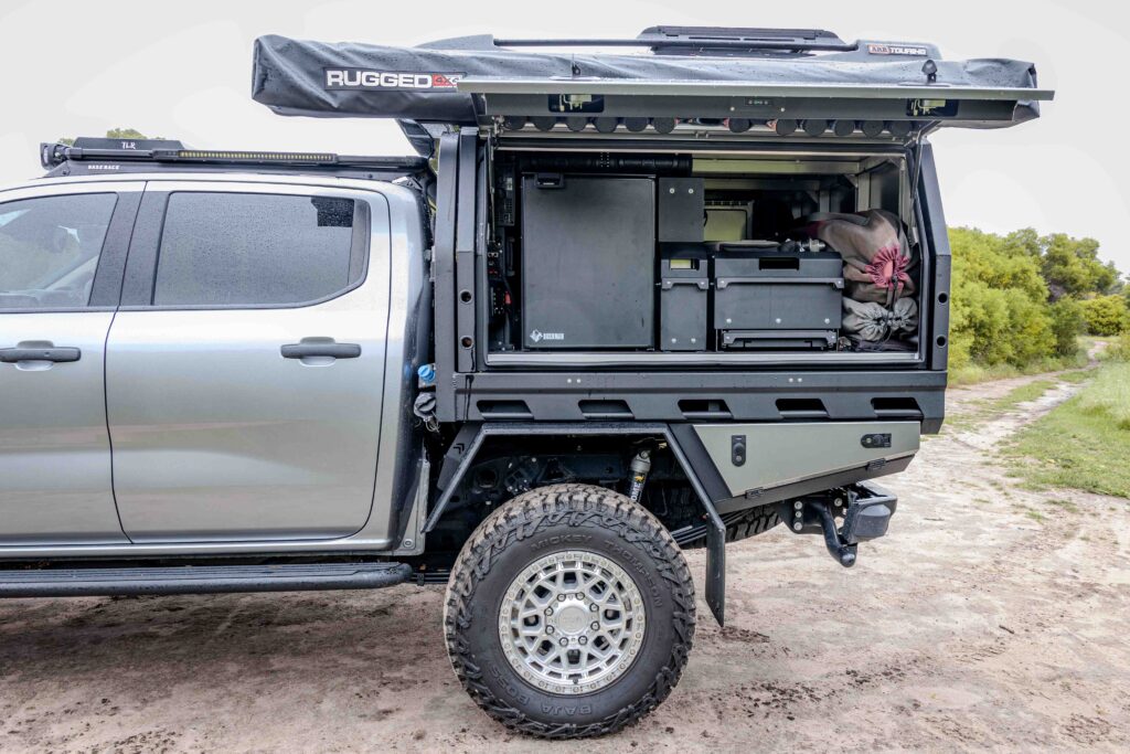 Open MITS Alloy canopy on a Ford Super Duty showing the Bushman upright fridge, storage drawers and touring setup