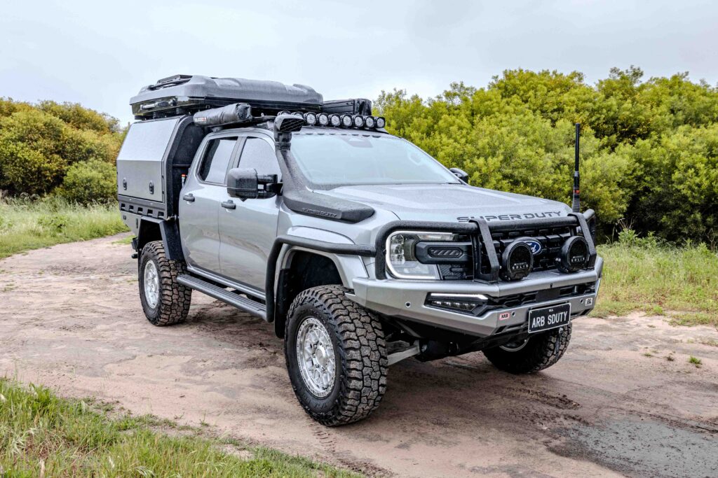 Front three-quarter view of a Ford Super Duty fitted with ARB protection, MITS Alloy canopy, roof rack and touring accessories