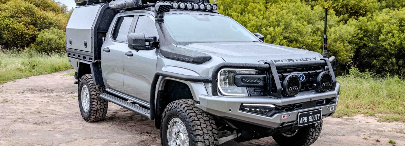 Front three-quarter view of a Ford Super Duty fitted with ARB protection, MITS Alloy canopy, roof rack and touring accessories