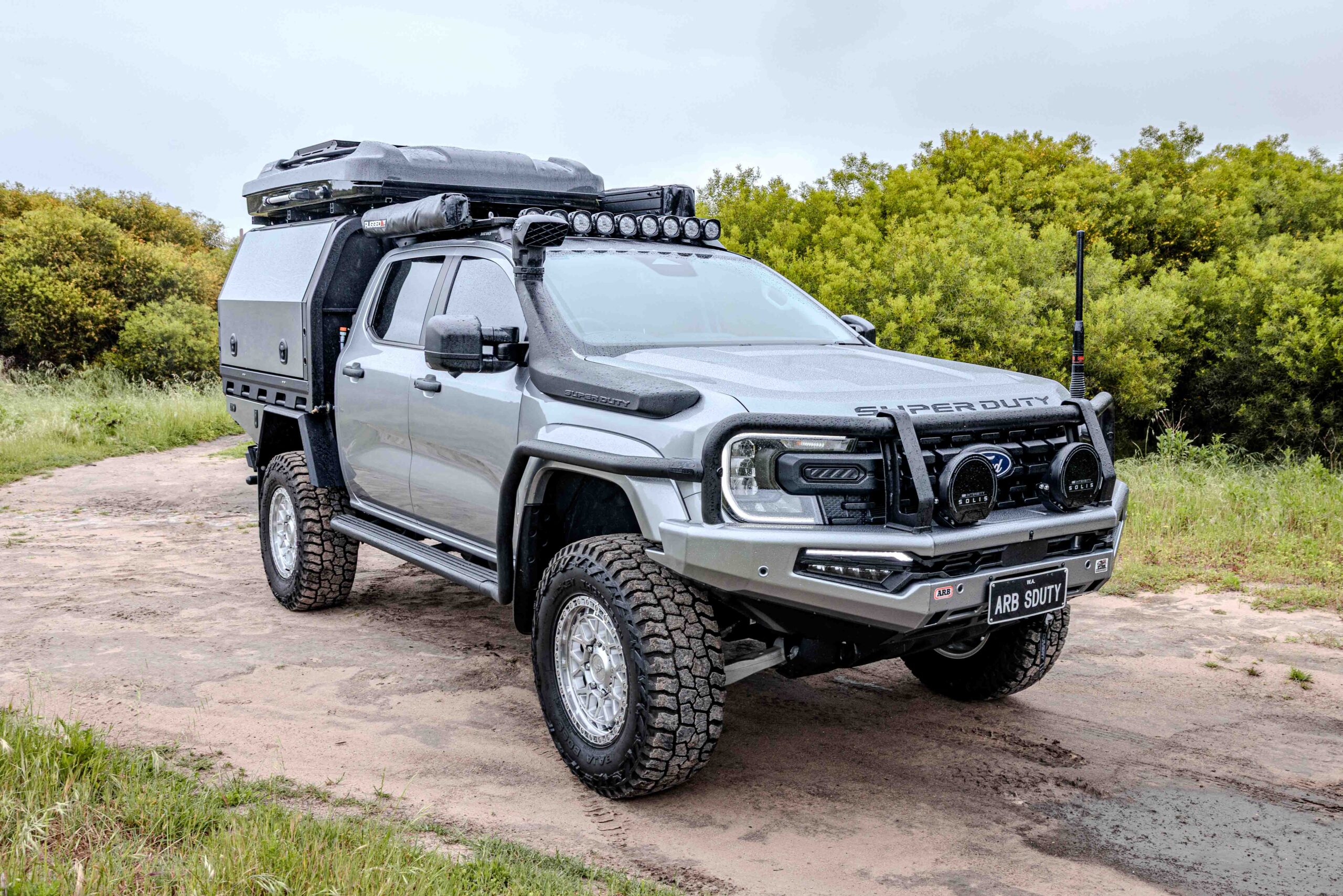 Front three-quarter view of a Ford Super Duty fitted with ARB protection, MITS Alloy canopy, roof rack and touring accessories