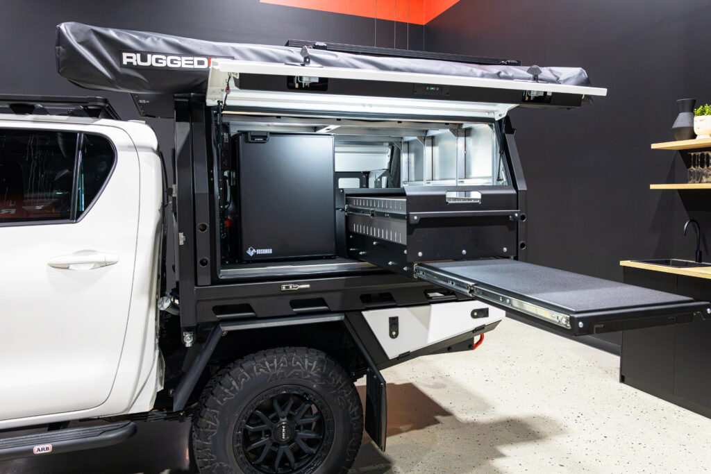 Open Toyota Hilux MITS Alloy canopy showing pull-out drawer, table, Bushman fridge and organised touring storage