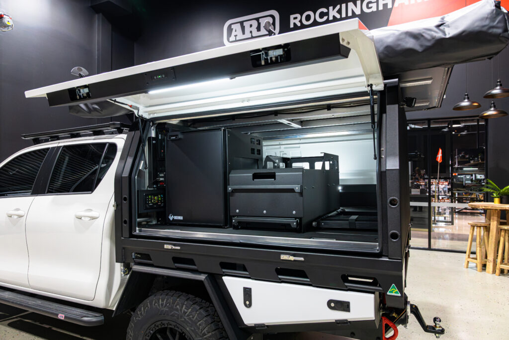 Open MITS Alloy canopy showing Bushman 85L upright fridge, electrical system, drawer storage and touring setup
